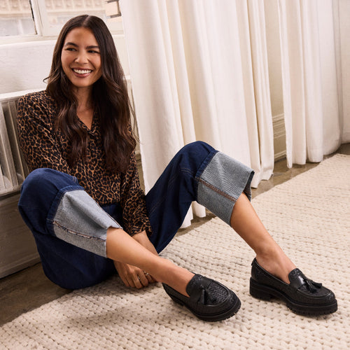 On figure image of the black woven faux leather with tassel Cara loafer