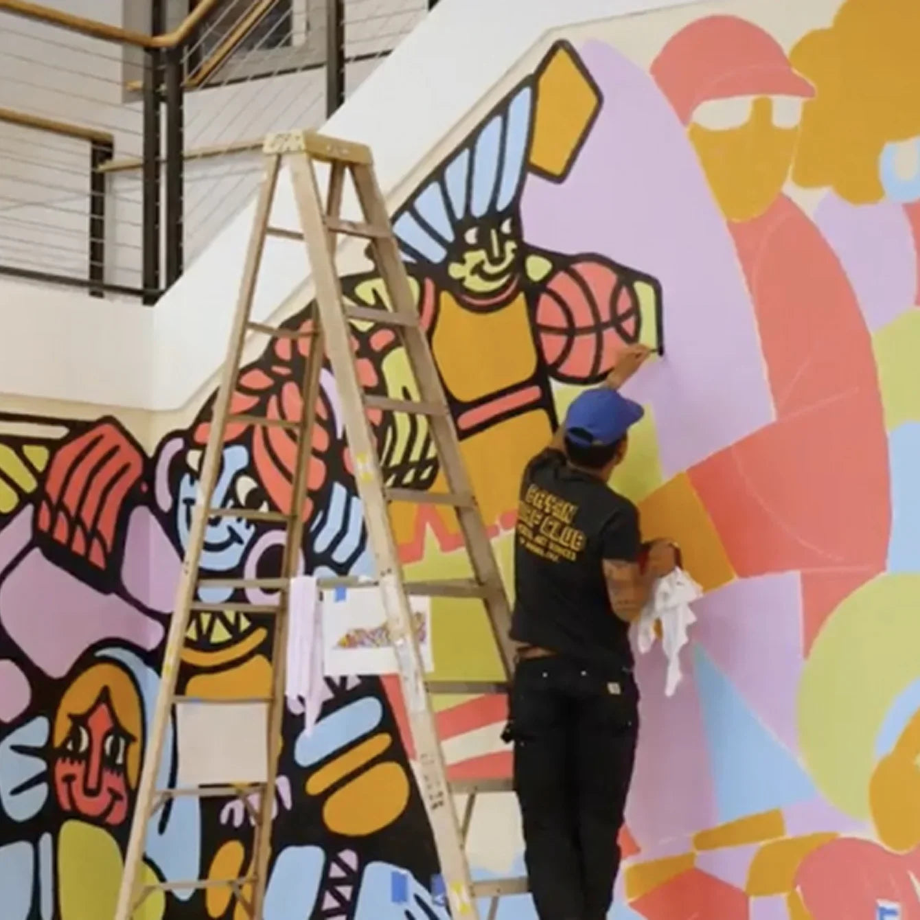 Someone painting a mural at TOMS HQ shown.