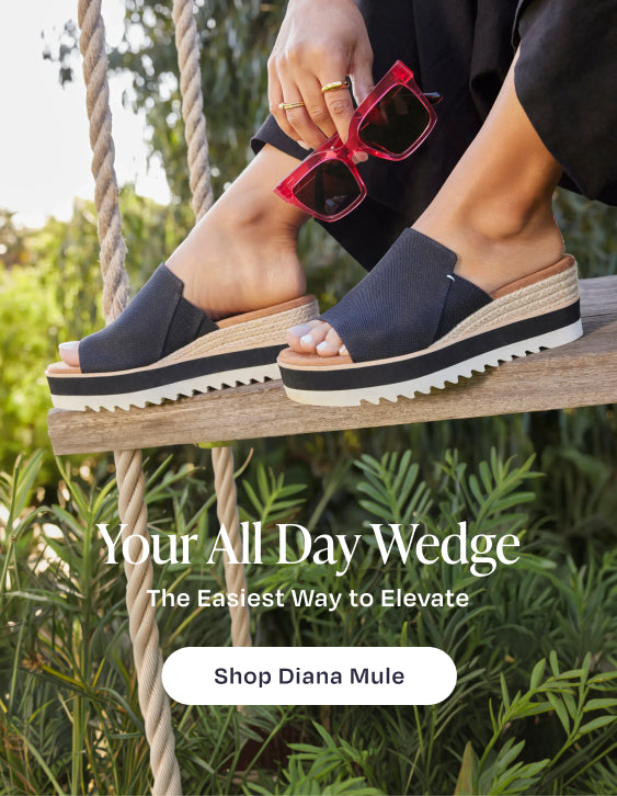 Your All Day Wedge. The Easiest Way to Elevate. Shop Diana Mule: model in Black Heavy Canvas, sitting on swing. Park background.