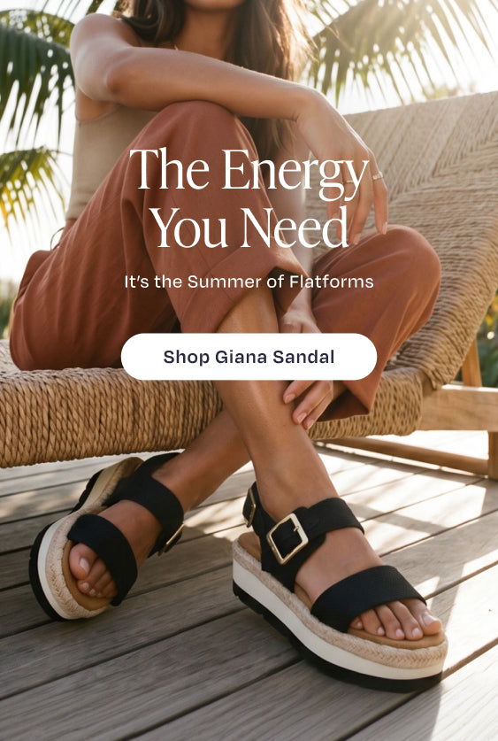 The Energy You Need. It's the Summer of Flatforms. Shop Giana Sandal: model in Black Woven, beach house background.