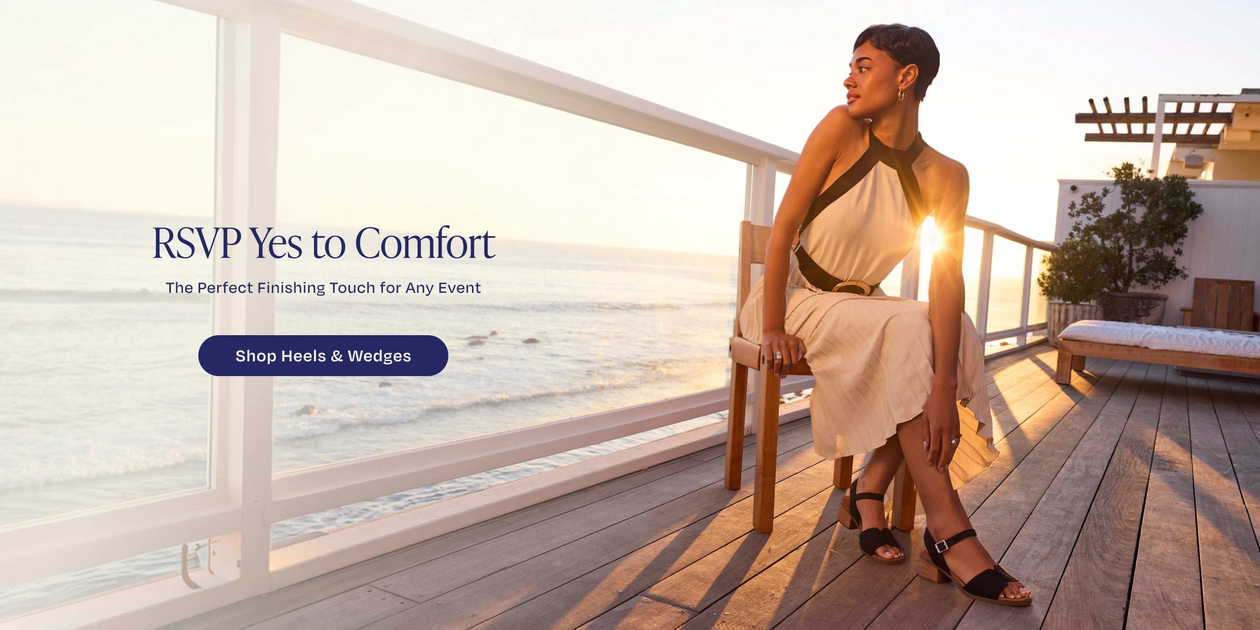 RSVP Yes to Comfort. The Perfect Finishing Touch for Any Event. Shop Heels & Wedges: model wearing Eloise Sandal in Black Woven, beach & sunset background.