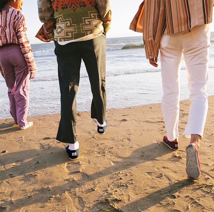 A group of friends walking on the beach in TOMS.