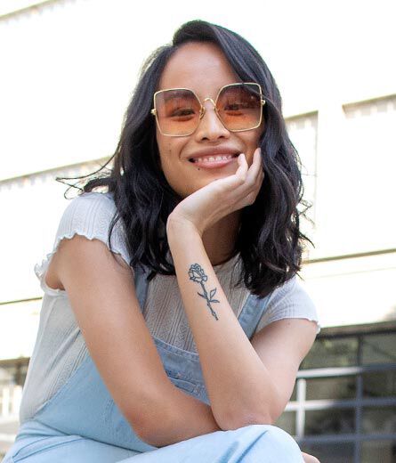 A woman smiles and wears TOMS sunglasses 