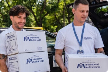 Two people holding International Medical Corps boxes.