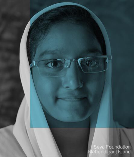 Featured: A young woman smiling wears glasses, image from the Seva Foundation in Mehendiganj Island
