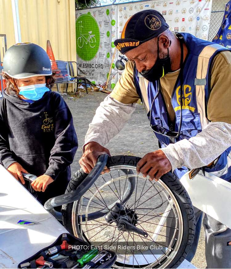 A man helping a boy with a bike tire.