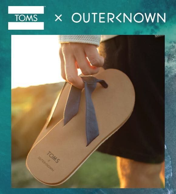 Green ocean and someone holding a pair of TOMS X Outerknown sandals